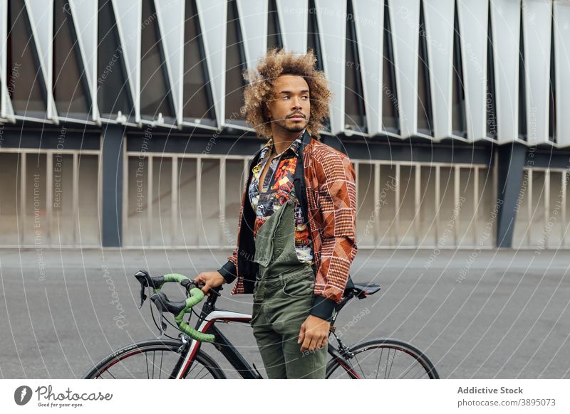 Ethnic man with bicycle standing on city street hipster urban young trendy bike commute informal traveler african american black ethnic lifestyle male