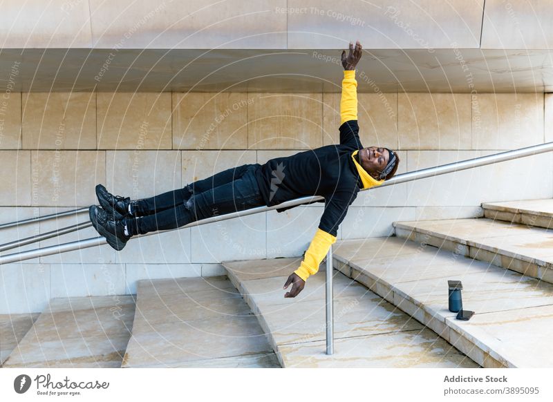 Young black man lying on railing hipster having fun step cheerful stair trendy style guy young african american ethnic male modern outstretch happy optimist