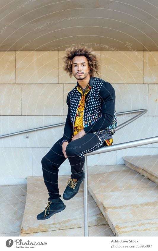 Stylish hipster ethnic man sitting on railing - a Royalty Free Stock Photo  from Photocase