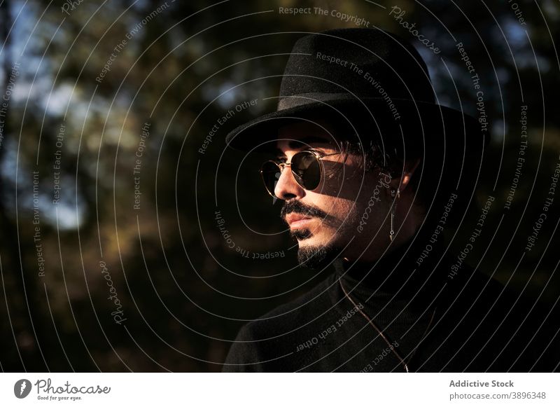 Stylish man in hat and sunglasses standing on meadow hipster style beard traveler piercing young male trendy modern handsome confident eyewear appearance