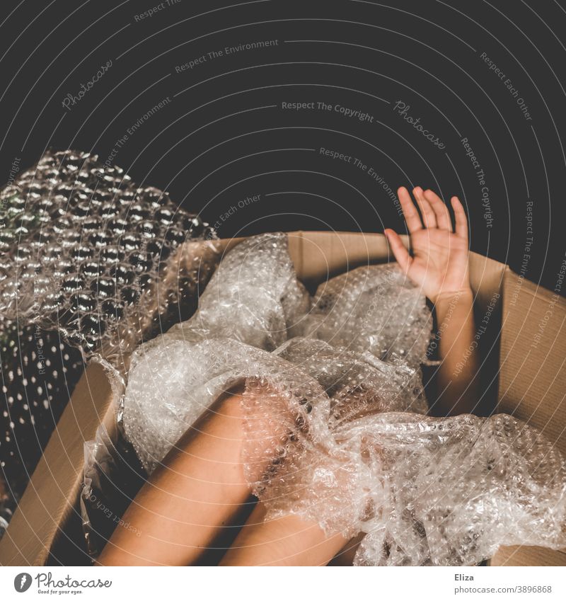 Man in a cardboard box, limbs peeking out between plastic packing material Cardboard Naked Package Shipping carton Human trafficking Packaging material