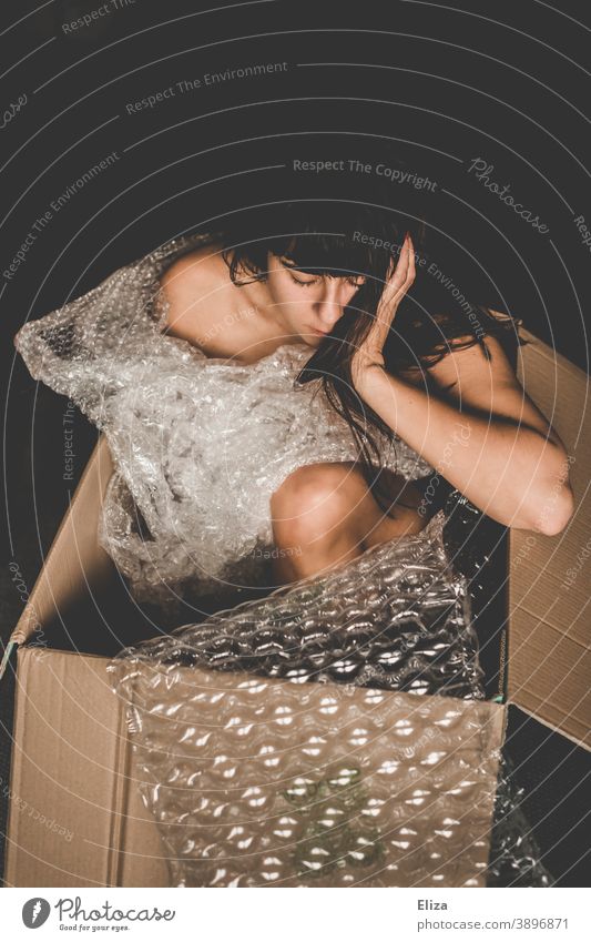 Back view of sensual naked woman sitting in limits of carton box looking up  stock photo