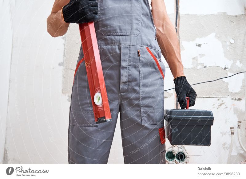 professional repairman in uniform holding hammer and toolbox home