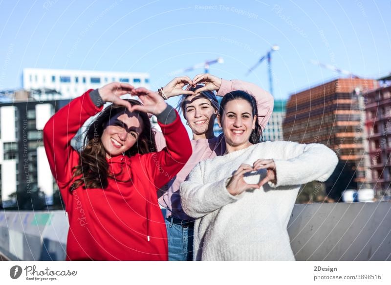 Portrait of three young woman showing finger gesture heart while smiling girl outdoor love female bonding closeness friendship gesturing flirting relationship