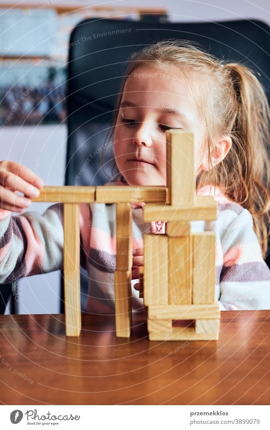 Little girl preschooler playing with wooden blocks toy building a house activity brick child childhood concept construction creativity education fun funny game