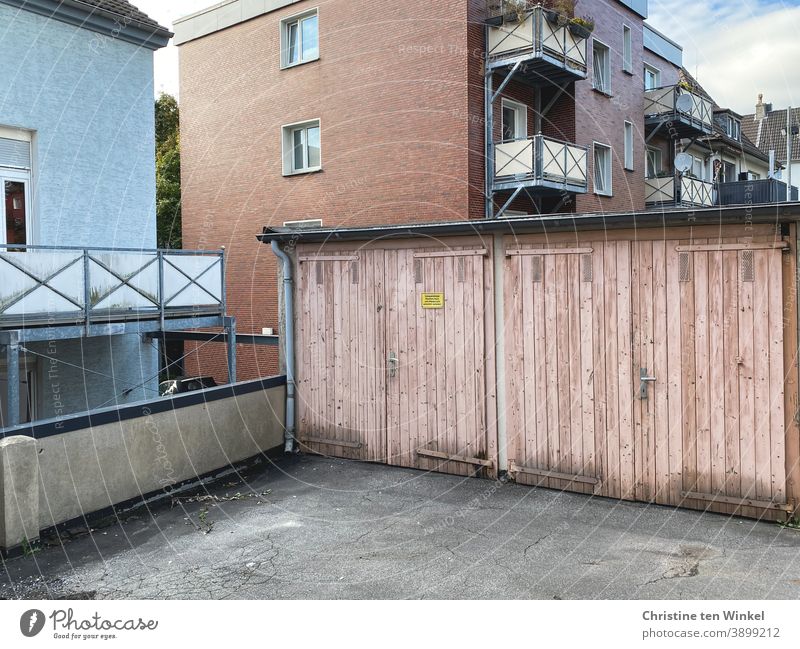 Neighborhoods | backyard with a view of two old pink garage doors and the windows and balconies of the apartment buildings behind Backyard garages Garage door