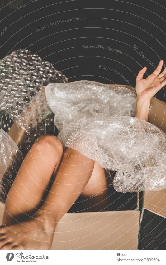 Man in a cardboard box between plastic packaging material Cardboard Human being Packaged Packaging material wrapped dispatch Goods Human trafficking Plastic