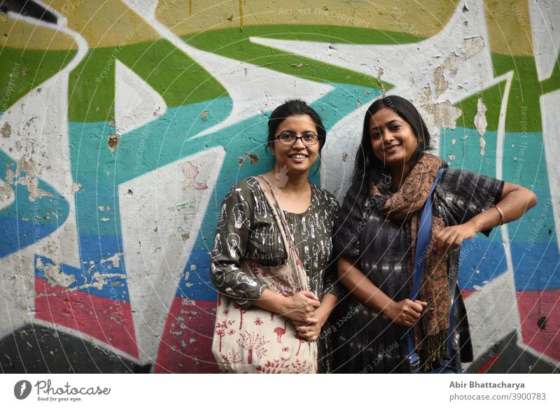 Portrait of two Indian Bengali brunette women/friends/sisters in front of a graffiti wall. Indian lifestyle actress adult asian attractive background beautiful