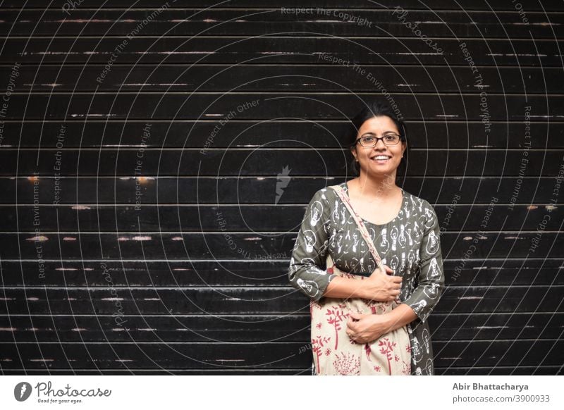 Portrait of an Indian Bengali brunette woman in front of a wall/ metallic gate/ black textured background. Indian lifestyle actress adult asian attractive