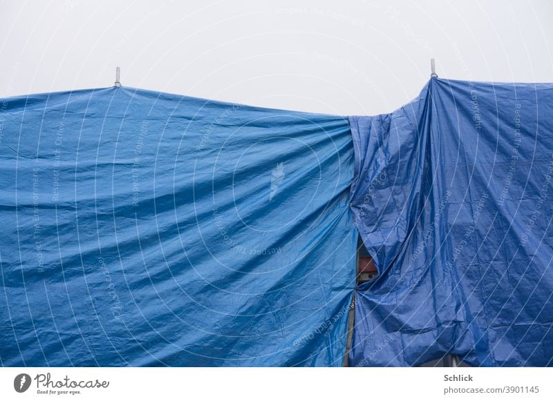 Hides scaffolding and roof covered with blue plastic tarpaulins Protection from rain Blue construction shrouded Colour photo Exterior shot Deserted