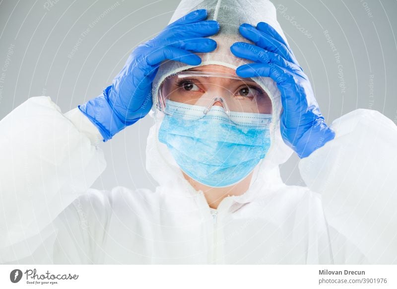 Desperate medical NHS EMS worker in white protective suit,blue surgical mask latex gloves & safety goggles,Coronavirus COVID-19 pandemic crisis causing shortage of protective personal equipment supply