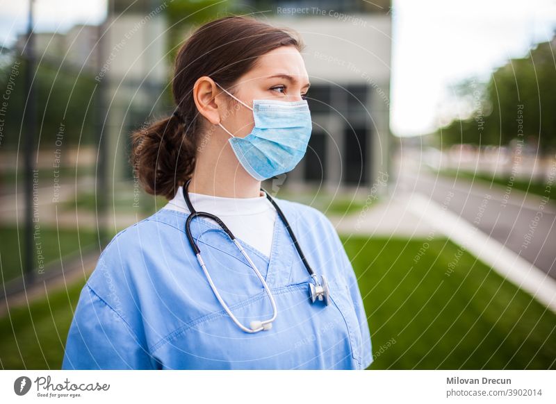Close up of female UK NHS EMS doctor's face,wearing blue PPE surgical  protective mask,COVID-19 Coronavirus disease,global pandemic  outbreak,deadly SARS-CoV-2 epidemic,copy space on left side of frame - a  Royalty Free Stock Photo