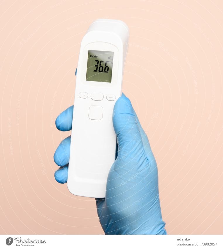 hand in blue latex gloves hold an electronic thermometer to measure temperature technology test tool treatment virus white body check checkup contactless