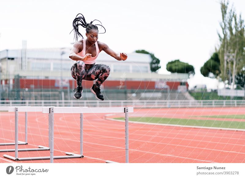 African-American athlete sprinter jumping a hurdle determined muscular afro american beginning african ambition motivation movement dynamic workout training