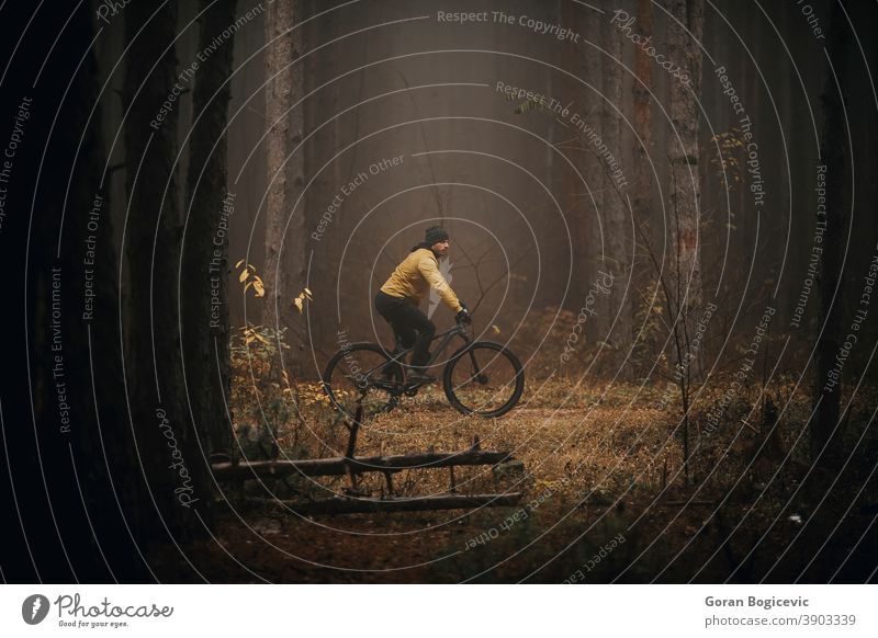 Young man biking through autumn forest action active activity adventure athlete bicycle bicycling bicyclist bike biker exercise extreme fast guy handsome