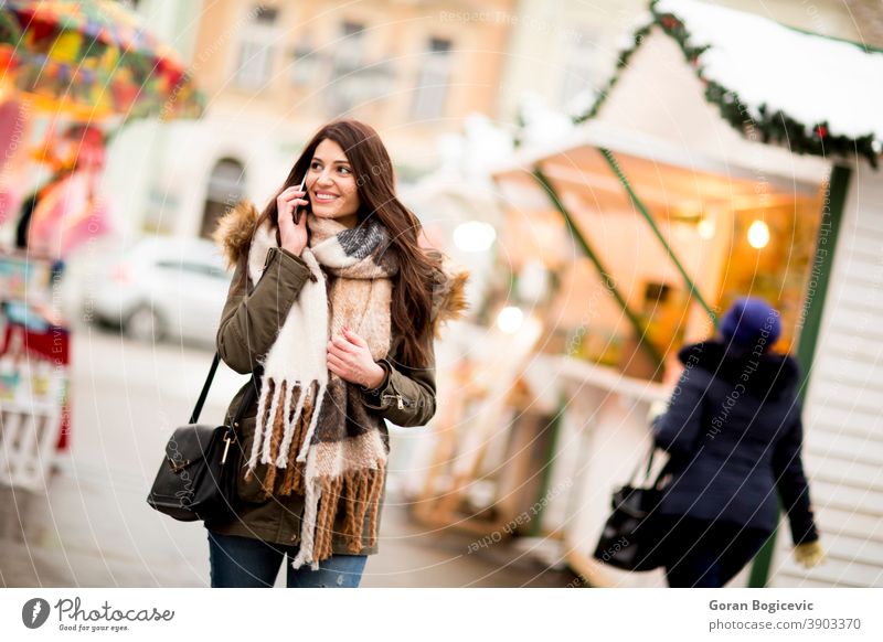 Happy fashion woman using a smart phone on street in winter at Christmas market attractive beautiful christmas new year cellphone city device female happy