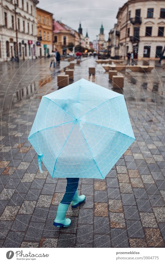 Child holds large blue umbrella in his hand and walks through the city centre on a rainy, gloomy autumn day rains Outdoors Little Autumn seasonal To fall