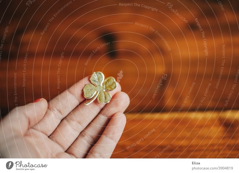 Hand holds a golden four-leaf clover. Lucky charm for New Year's Eve. Good luck charm Happy Cloverleaf Four-leaved Four-leafed clover turn of the year
