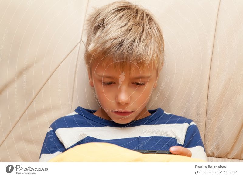 Little kid playing game or watching something on mobile smart phone bed bedtime boy caucasian cell phone cellphone child childhood communication connection cute