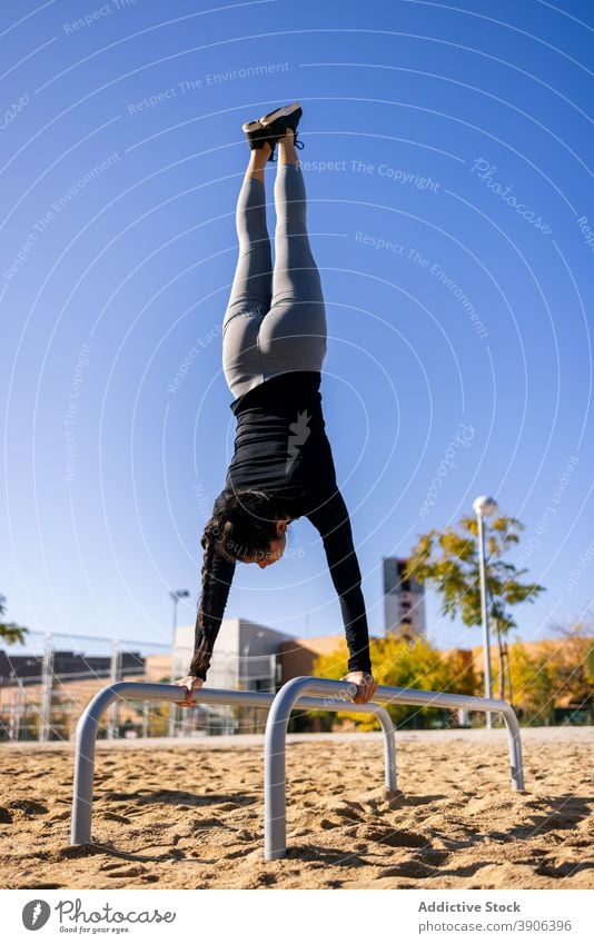 Strong sportswoman balancing on parallel bars in splits handstand calisthenics training balance strong effort female athlete fit practice fitness vitality slim