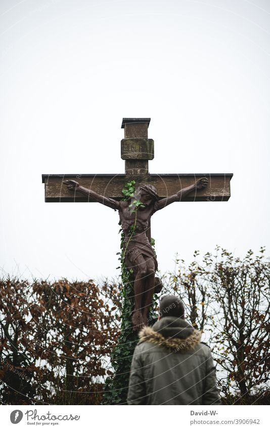 Man standing in front of an old cross surrounded by climbing plants Crucifix Religion and faith God oblivion Hope Christian cross Jesus Christ pray