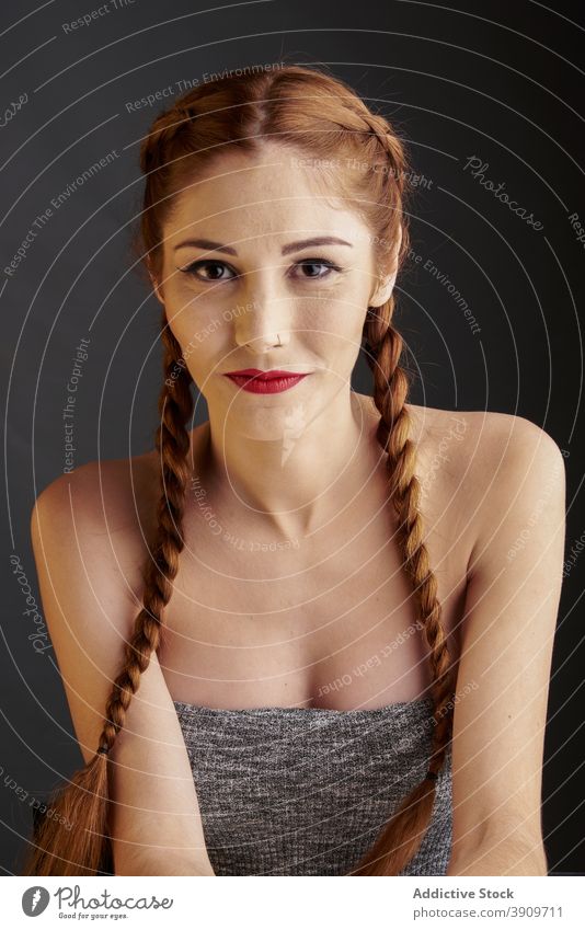 Woman with braids in studio looking at camera redhead hairstyle woman appearance charming trendy red hair female red lips model personality individuality