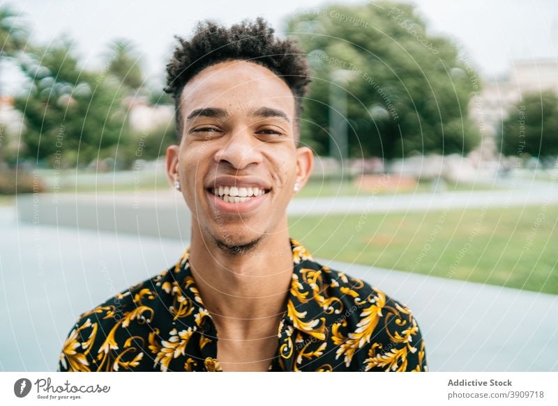 Positive black man smiling at camera smile trendy handsome portrait cheerful young afro hairstyle city male ethnic african american apparel fancy happy modern