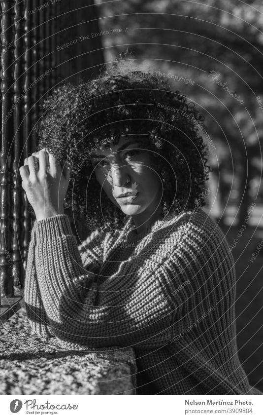 Grayscale shot of a beautiful female with curly hair standing near a metallic fence. portrait Black & white photo woman afro hairstyle black young casual
