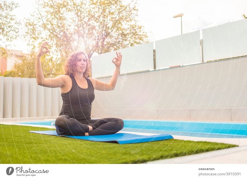 Middle aged woman doing yoga execises in her home garden - a