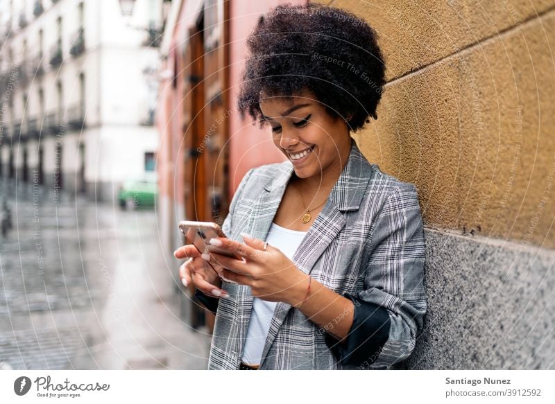 Pretty Afro Woman Using Phone woman afro portrait black woman using phone street city life cellphone smartphone communication technology type typing texting