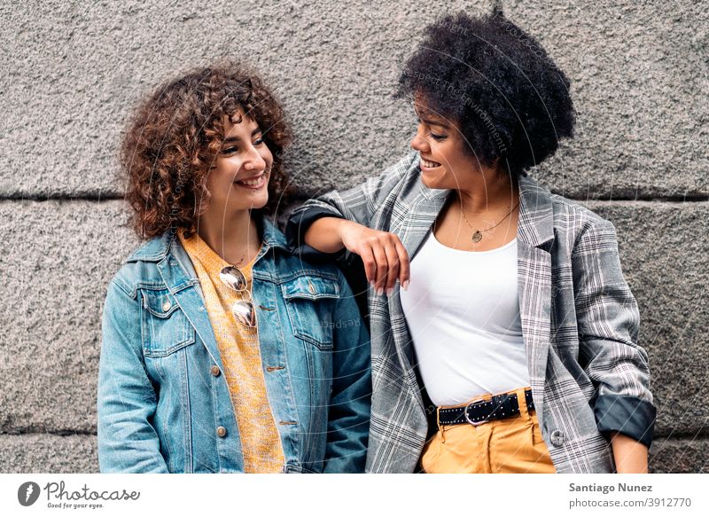 Cool Afro Girl and Friend Smiling women looking at each other street multi-ethnic afro girl caucasian portrait having fun front view friends friendship