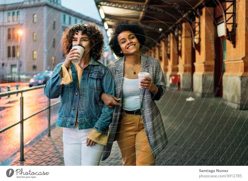 Afro Girl and Friend in Street cup of coffee walking street friends drinking looking at camera women multi-ethnic afro girl caucasian portrait having fun