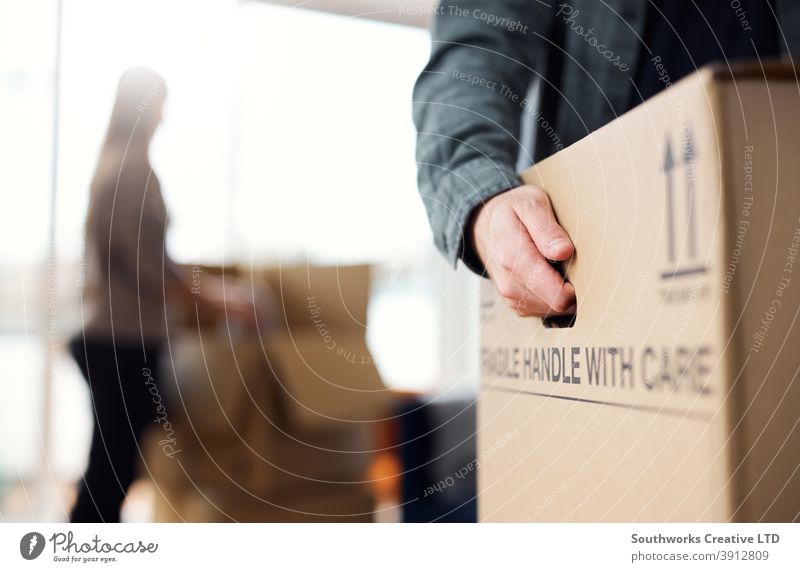 Close Up Of Man Carrying Removal Box As Couple Move In Or Out Of New Home couple young couple house buying packing moving out moving house upgrading carrying