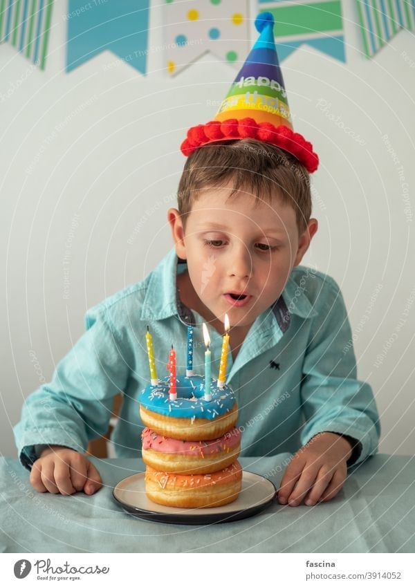 Child blows out the candle on birthday donuts cake - a Royalty Free ...