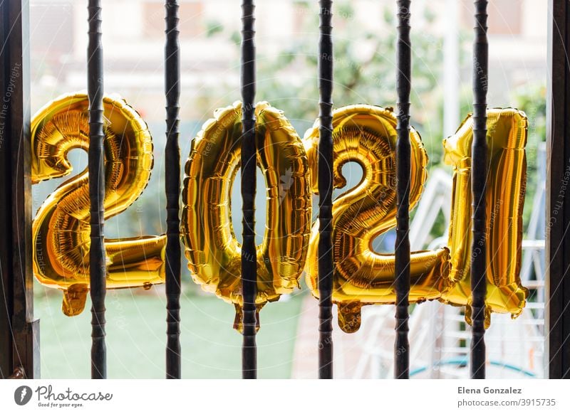 Gold foil balloons numeral 2021 behind bars confined starting the year. coronavirus crisis concept. Balloons jail confines confinement gold new year beginning