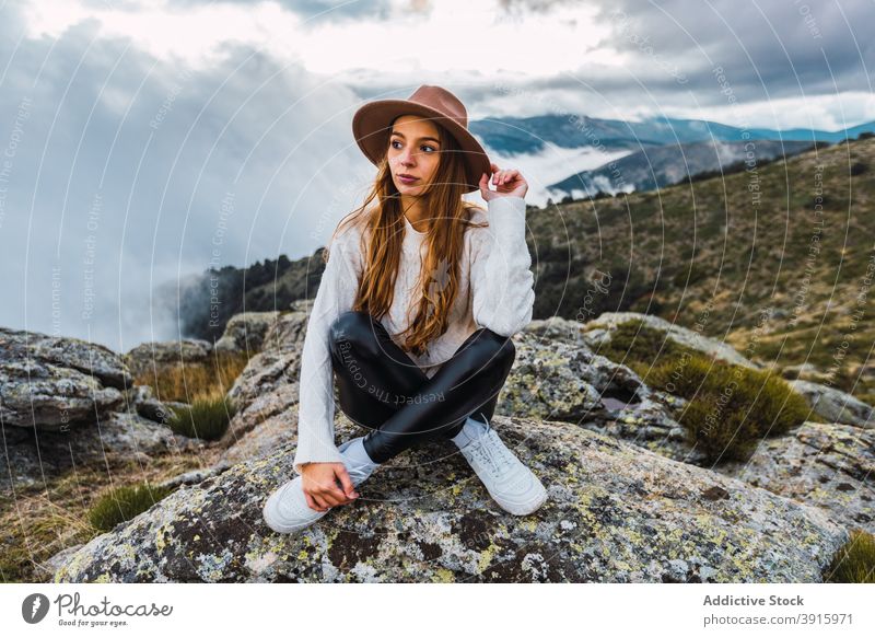 Woman in hat enjoying view of mountains woman observe viewpoint travel tourist highland admire explore female stone scenic sit nature traveler picturesque