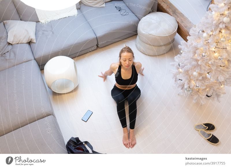 Beautiful blonde woman doing home workout indoors. Woman practice yoga at  home. Fit girl using workout tutorials for healthy active lifestyle. Woman  using quarantine for home workouts. - a Royalty Free Stock