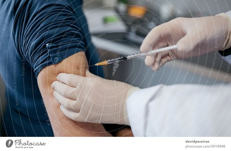 Arm of unrecognizable adult receiving coronavirus vaccine vaccination syringe covid-19 closeup arm doctor hand patient needle injecting immunization senior