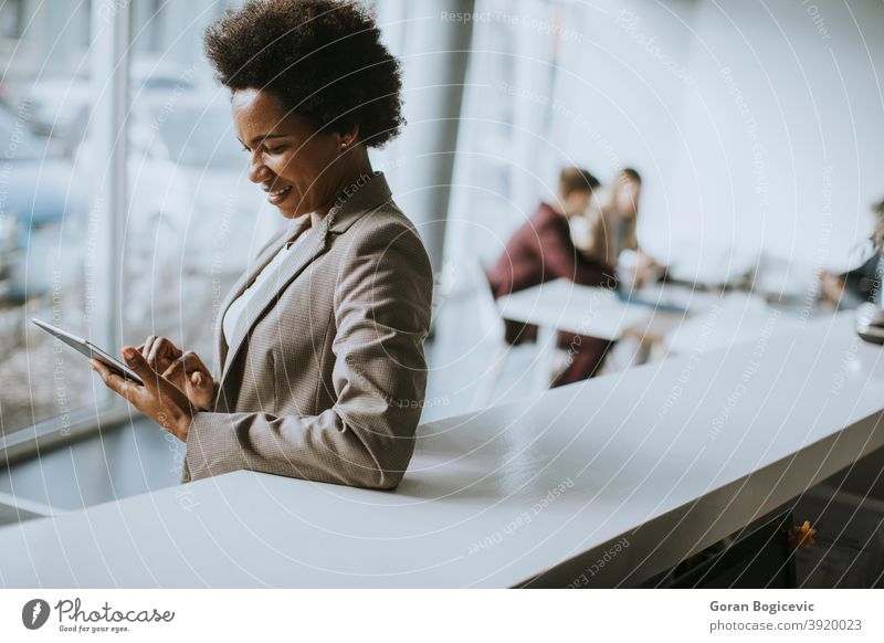 African American businesswoman standing and using digital tablet in a modern office adult african afro american beautiful black cheerful communication confident