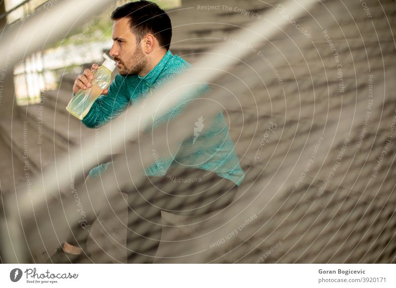 Young man resting during training with bottle of water fitness male young urban workout sport athlete active athletic city health lifestyle healthy body