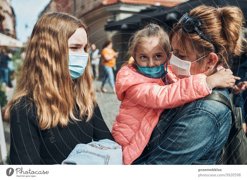 Family mother and her daughters standing in a street downtown wearing the face masks to avoid virus infection call care caucasian chat contagious corona
