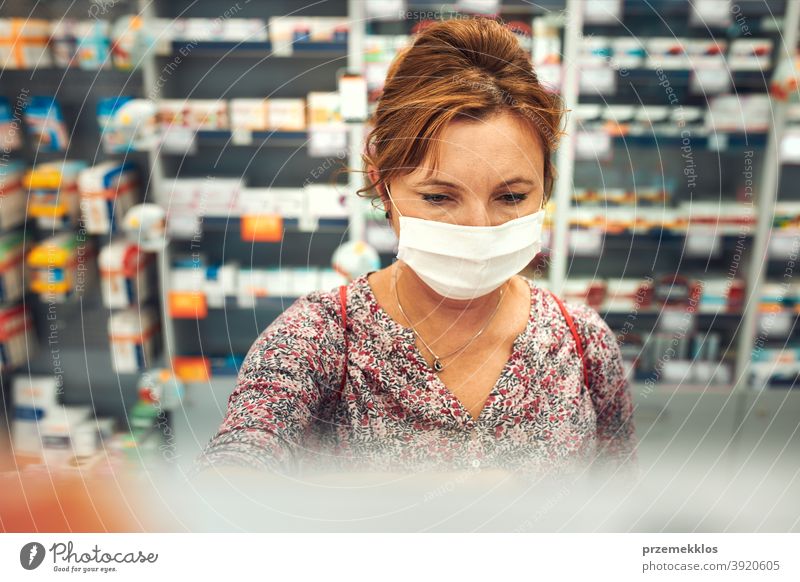 Woman shopping at pharmacy, buying medicines, wearing face mask during pandemic coronavirus outbreak woman chemist covid-19 cover standing town female care