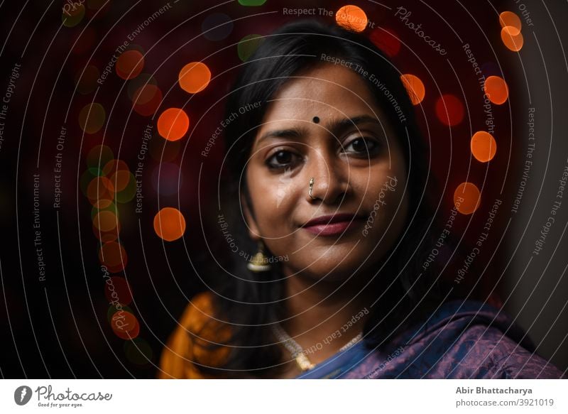 Face portrait of a smiling Indian woman in light bokeh background adult art asian beautiful bengali celebration cheerful clothing culture diwali celebration
