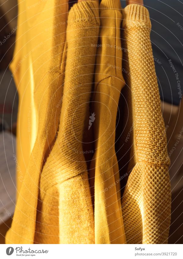 Yellow illuminated color winter sweaters on hangers yellow autumn cashmere fall background knit cozy fashion warm knitwear fabric soft woolen girl apparel