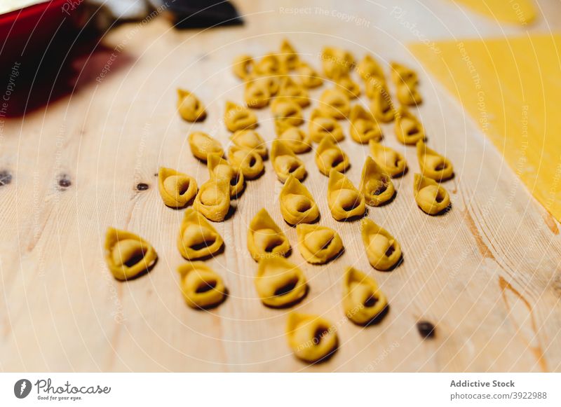 Traditional raw tortellini on wooden table in kitchen italian food dumpling homemade domestic uncooked dough pastry italian cuisine prepare culinary tradition