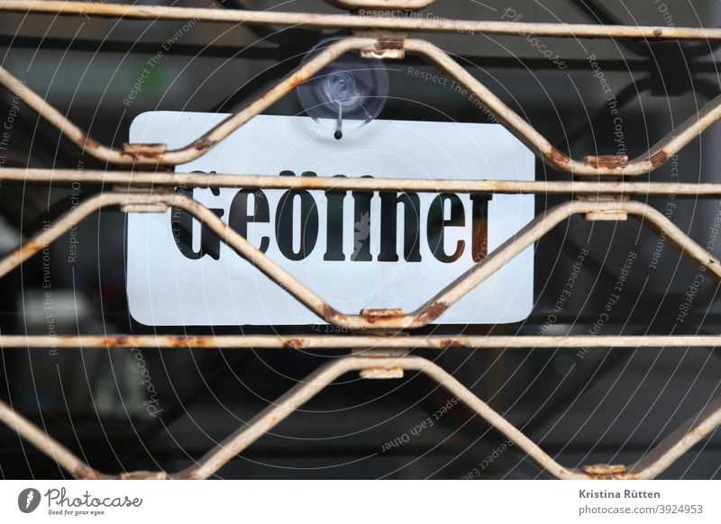 open sign behind closed rolling grille Notice roller grilles Grating Closed locked too Conflicting Disagreement door Entrance opening hours Opening time