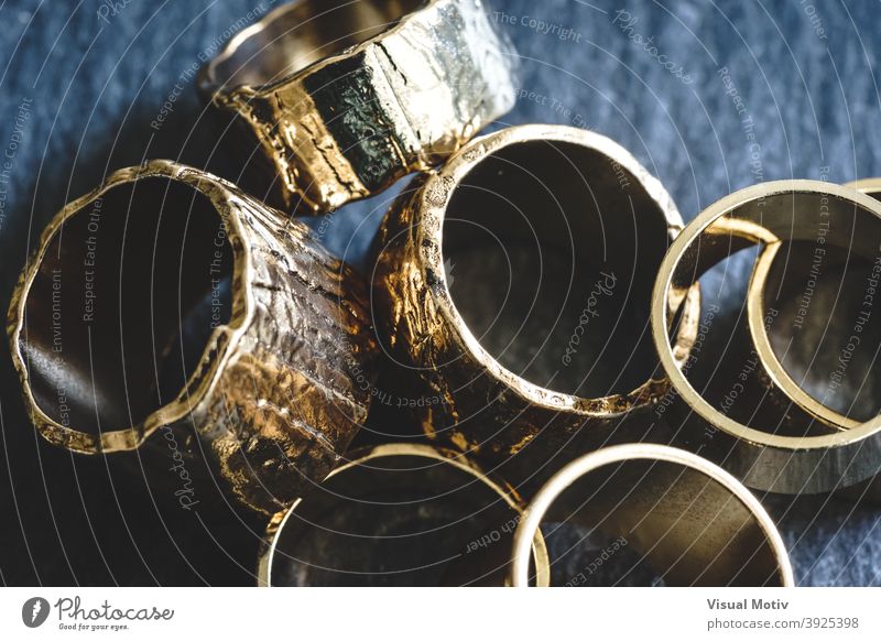Close-up of several golden rings piled on a slate board abstract detail close-up fashion chic shiny design metallic decorative objects bijou interior macro