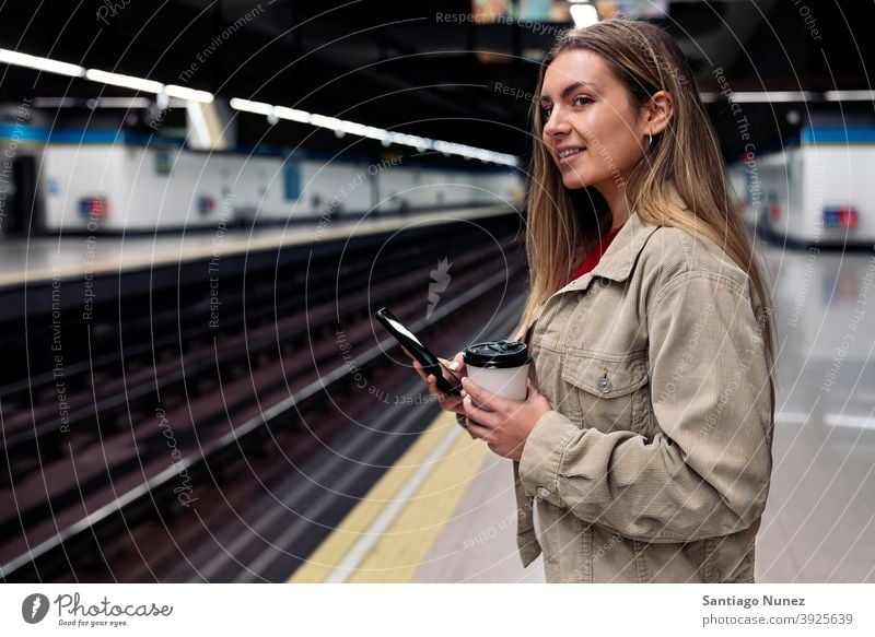 Young Girl Waiting in Train Platform side view woman caucasian train platform portrait using phone typing looking background standing female indoors outdoors