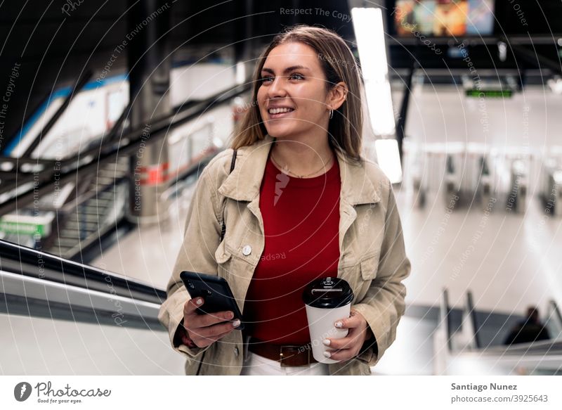 Happy Girl on Escalator stairs escalators station train station woman young girl cup of coffee phone using phone smiling front view smile portrait 20s blonde