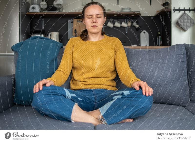 Woman practicing yoga at home woman meditating relaxation female sitting wellbeing wellness balance lifestyle person adult cross-legged exercising position